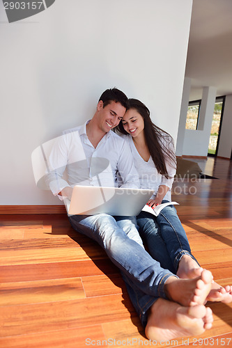 Image of relaxed young couple working on laptop computer at home