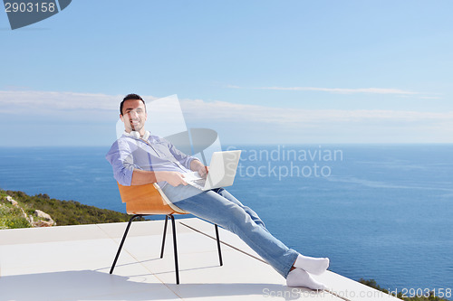 Image of relaxed young man at home on balcony