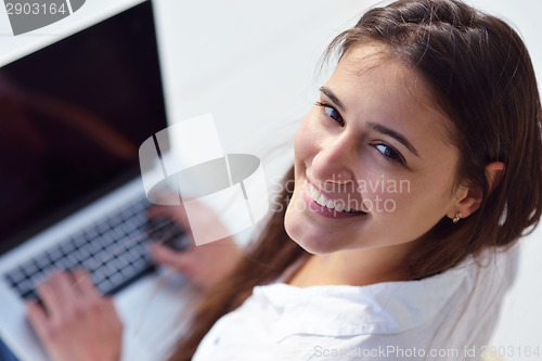 Image of relaxed young woman at home working on laptop computer