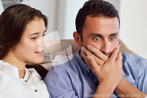 Image of relaxed young couple working on laptop computer at home