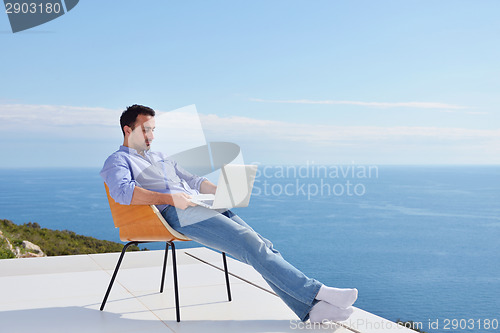 Image of relaxed young man at home on balcony