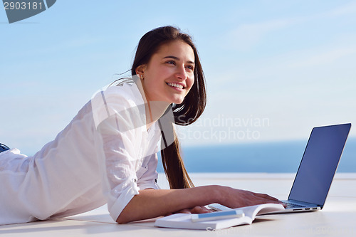 Image of relaxed young woman at home working on laptop computer