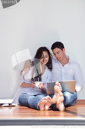 Image of relaxed young couple working on laptop computer at home