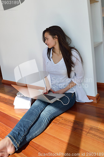 Image of relaxed young woman at home working on laptop computer