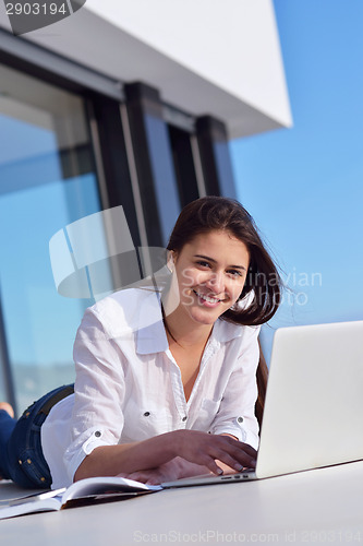 Image of relaxed young woman at home working on laptop computer
