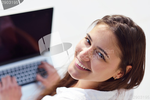 Image of relaxed young woman at home working on laptop computer
