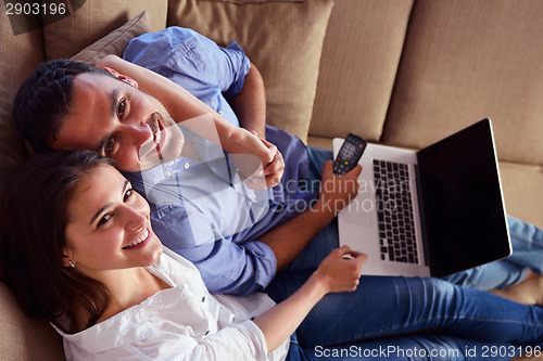 Image of relaxed young couple working on laptop computer at home
