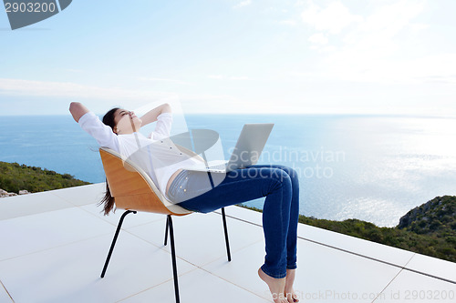 Image of relaxed young woman at home working on laptop