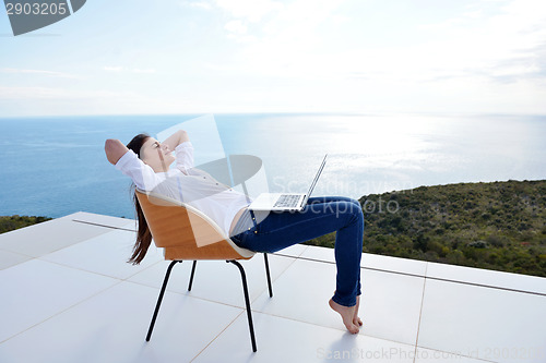 Image of relaxed young woman at home working on laptop