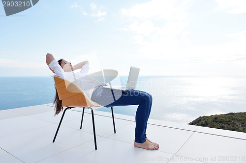 Image of relaxed young woman at home working on laptop