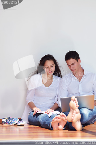 Image of relaxed young couple working on laptop computer at home