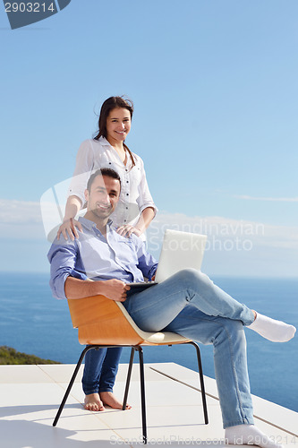 Image of relaxed young couple working on laptop computer at home
