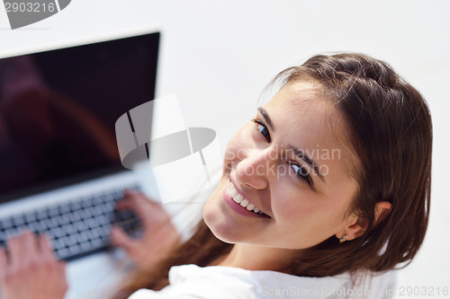 Image of relaxed young woman at home working on laptop computer