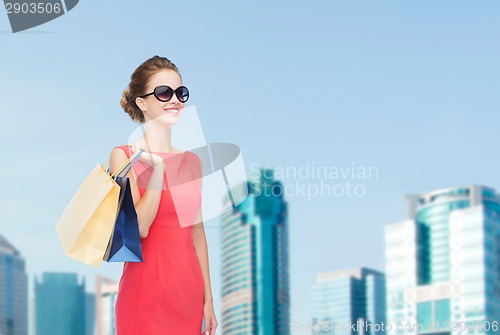 Image of smiling elegant woman in dress with shopping bags