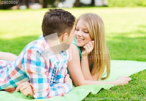 Image of smiling couple lying on blanket in park