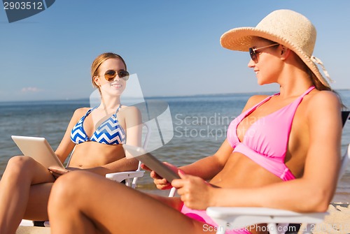 Image of smiling women with tablets pc computers on beach