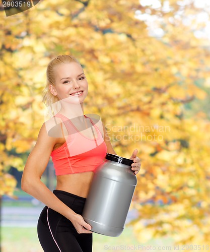 Image of smiling sporty woman with jar of protein