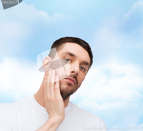 Image of beautiful calm man touching his face