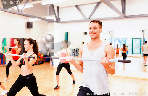 Image of group of smiling people working out with barbells