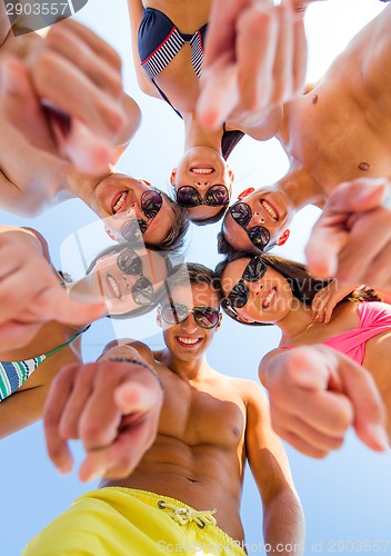 Image of smiling friends in circle on summer beach