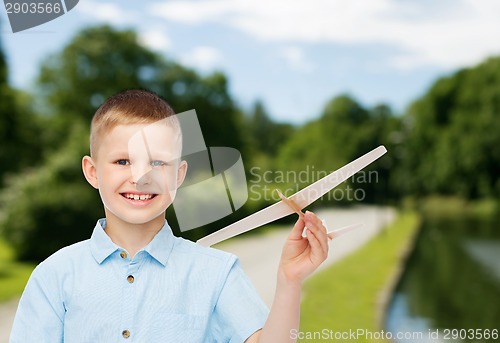 Image of smiling little boy holding a wooden airplane model