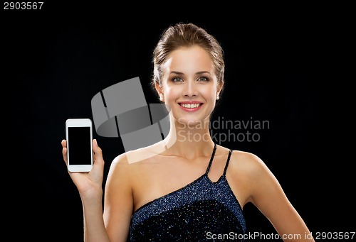 Image of smiling woman in evening dress holding smartphone