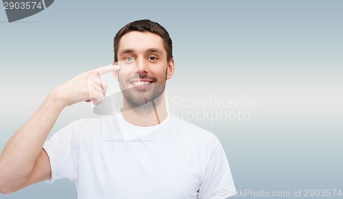 Image of smiling young handsome man pointing to eyes