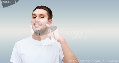 Image of smiling young handsome man pointing to cheek