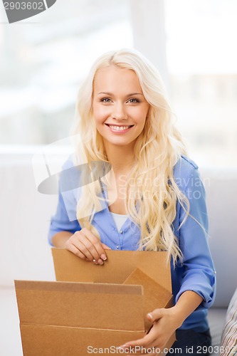 Image of smiling young woman opening cardboard box