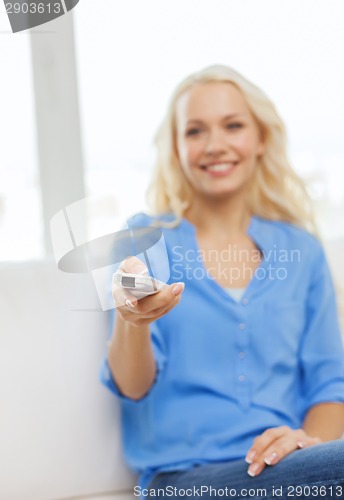 Image of smiling teenage girl with tv remote control