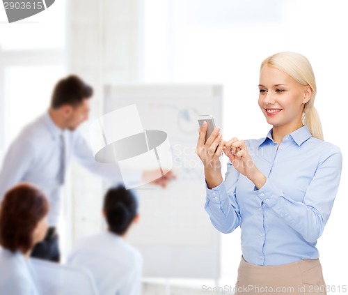 Image of young smiling businesswoman with smartphone