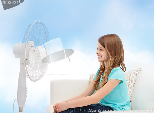 Image of smiling little girl with big fan at home