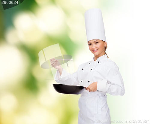 Image of smiling female chef with pan and spoon