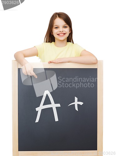 Image of happy little girl pointing finger to blackboard