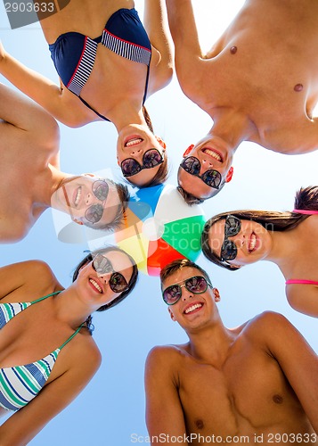 Image of smiling friends in circle on summer beach