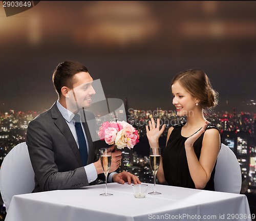 Image of smiling man giving flower bouquet to woman