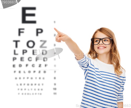 Image of cute little girl in eyeglasses pointing in the air