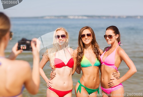 Image of group of smiling women photographing on beach