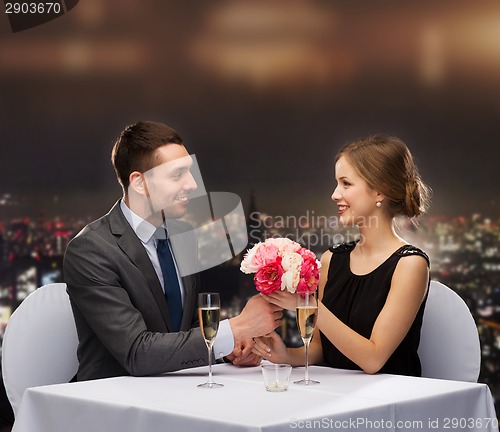 Image of smiling man giving flower bouquet to woman