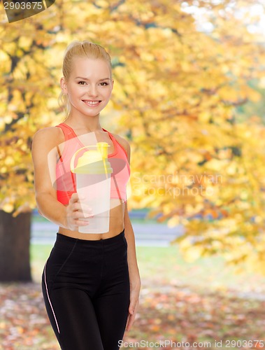 Image of smiling sporty woman with protein shake bottle