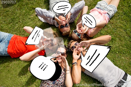 Image of group of smiling friends lying on grass outdoors