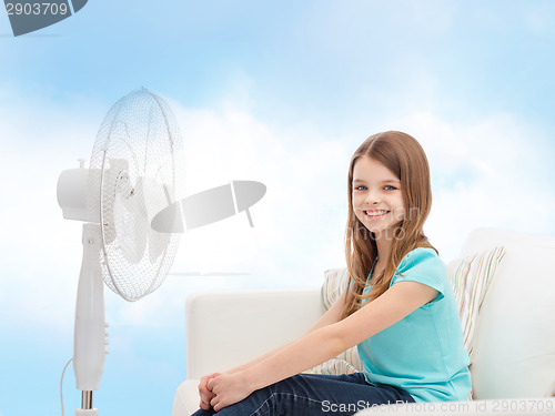 Image of smiling little girl with big fan at home