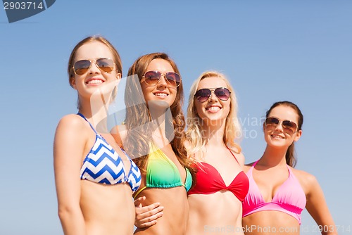 Image of group of smiling young women on beach