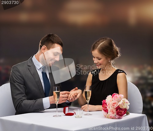 Image of man proposing to his girlfriend at restaurant