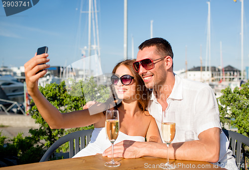 Image of smiling couple drinking champagne at cafe