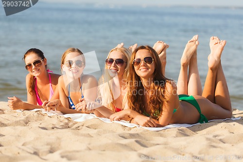 Image of group of smiling women in sunglasses on beach