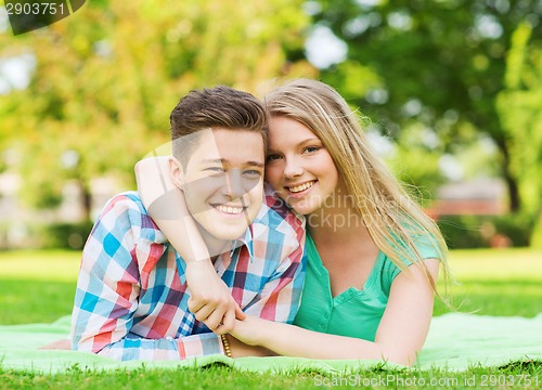 Image of smiling couple lying on blanket in park