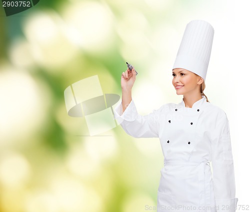 Image of smiling female chef writing something on air