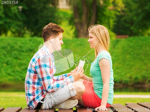 Image of smiling couple with smartphone and earphones