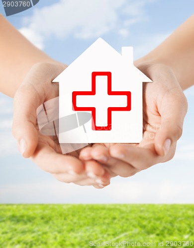 Image of hands holding paper house with red cross